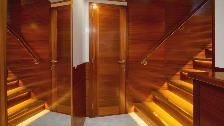 Eine Holztreppe mit Stufenbeleuchtung und Geländer führt in die nächste Etage.